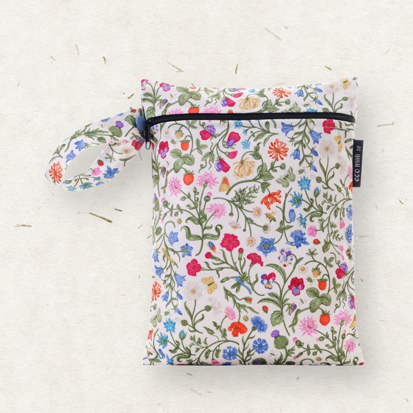 A small fabric wet bag with a colorful wildflower print on a cream background, featuring a top zipper, a matching wrist loop, and a black brand tag that reads 'ECO MINI.