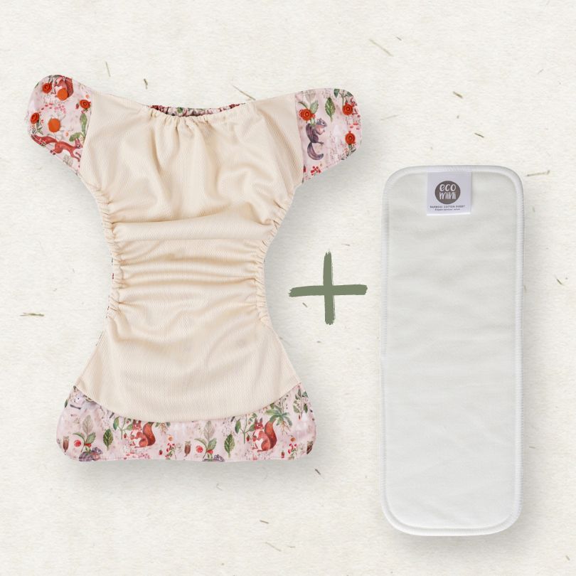 Eco Mini Reusable diaper with floral trim and a white pouch with a green plus sign on a light background