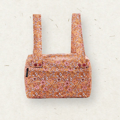 Eco Mini Cloth Diaper POD - with a dense floral and botanical print in orange, pink, and white, featuring two upright handles, photographed flat against a textured off-white background.