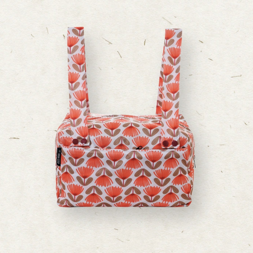 Eco Mini Cloth Diaper POD - with a retro mid-century floral pattern in coral orange, brown, and white, featuring two shoulder straps and a zippered top closure, set against a textured off-white background.