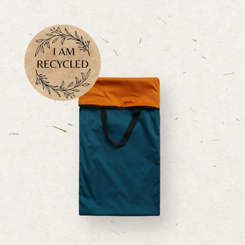 A dark teal Eco mini Large cloth diaper wet bag/ PUL påse with black handles, shown on a textured off-white background with a circular 'I AM RECYCLED' graphic overlay in the top 