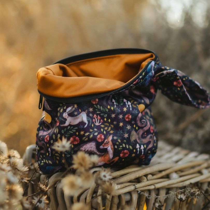 Small Eco Mini wet bag with nature-themed design on a woven surface with blurred natural background