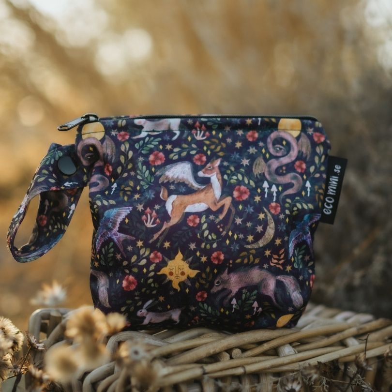 Small Eco Mini wet bag with nature-themed design on a woven surface with blurred natural background