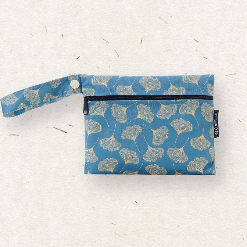 A blue wet bag with a wrist strap, decorated with a repeating ginkgo leaf pattern in beige and light blue, shown on a textured off-white background.