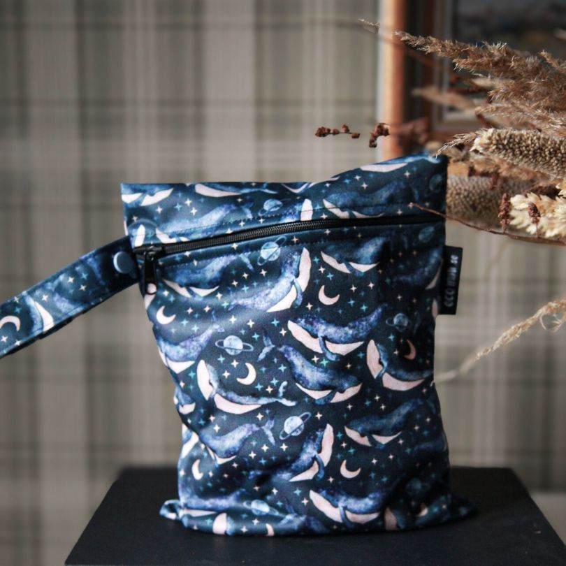 Eco Mini wet bag with whales print on a dark surface