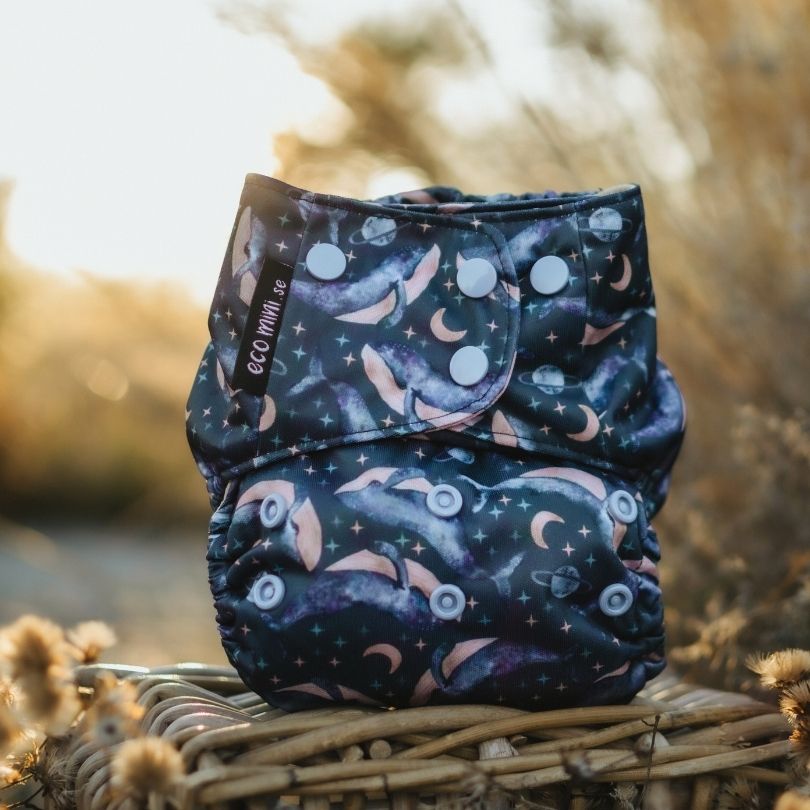 Patterned Eco Mini cloth diaper on a woven basket with a natural background