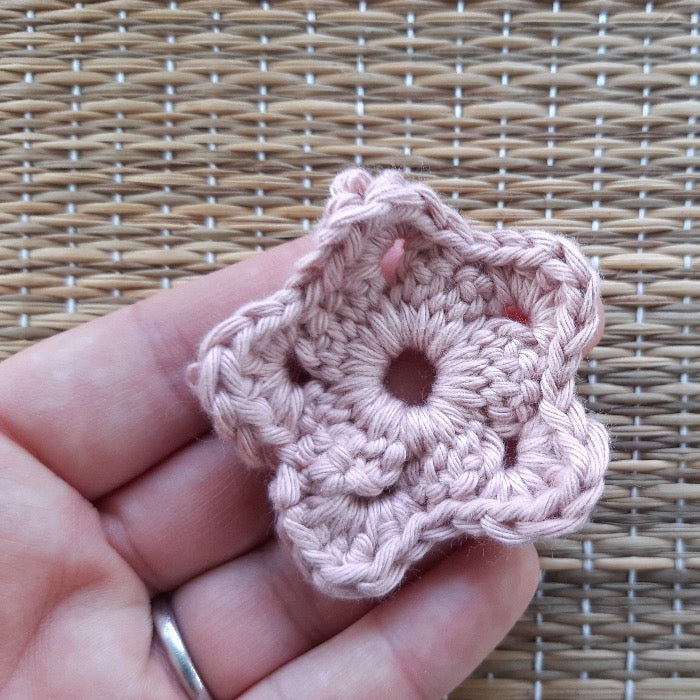 Coral coloured flower shaped face scrubby