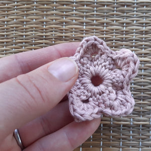 Coral coloured flower shaped face scrubby